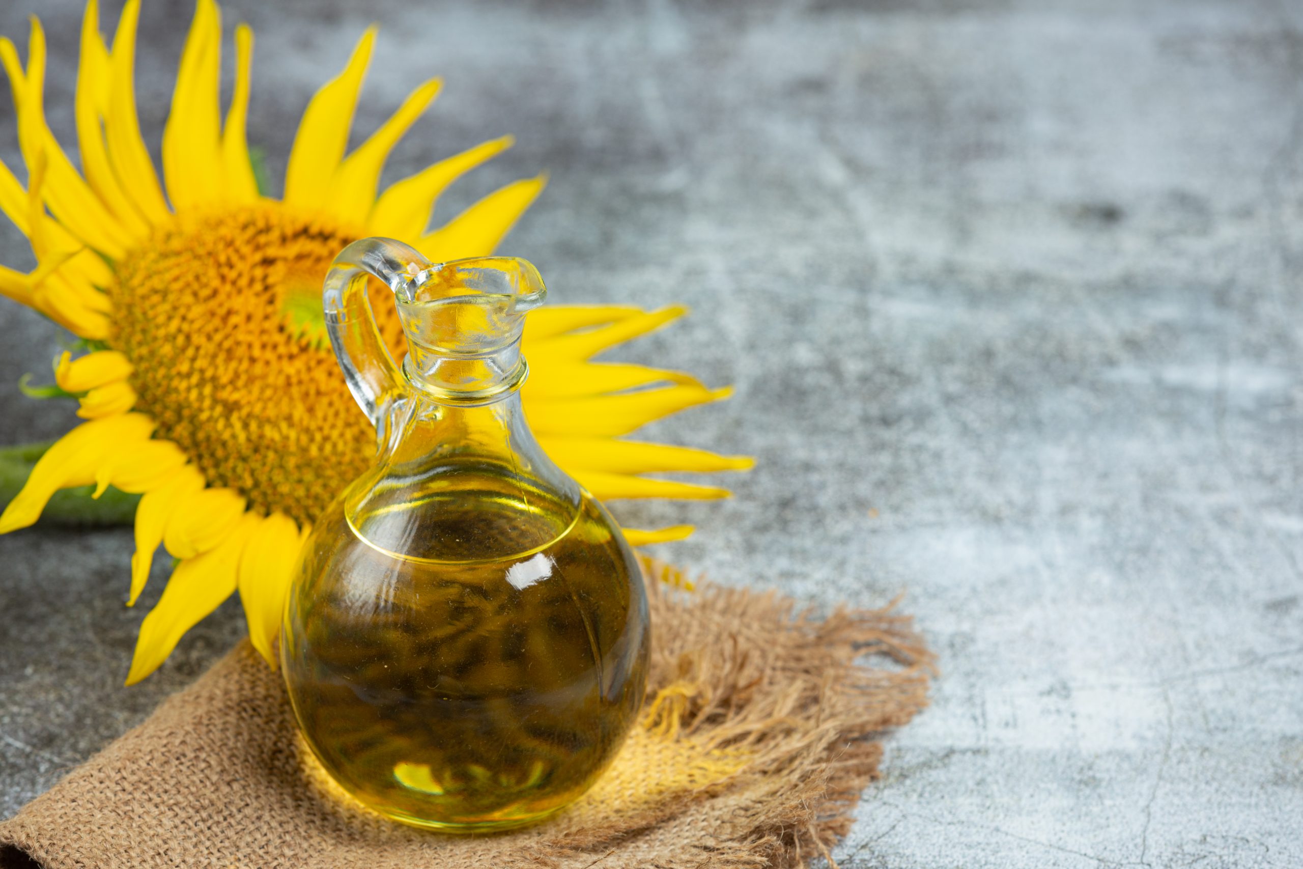 Little container of sunflower oil with a sunflower behind